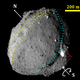 The asteroid, showing a ridge (yellow) and trough (light blue), with a red arrow pointing to a bright region